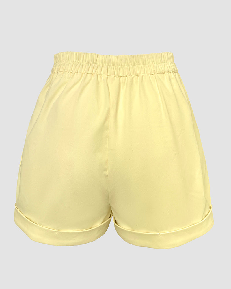 A light yellow V-neck sleeveless top with matching high-waisted shorts and rolled hems.