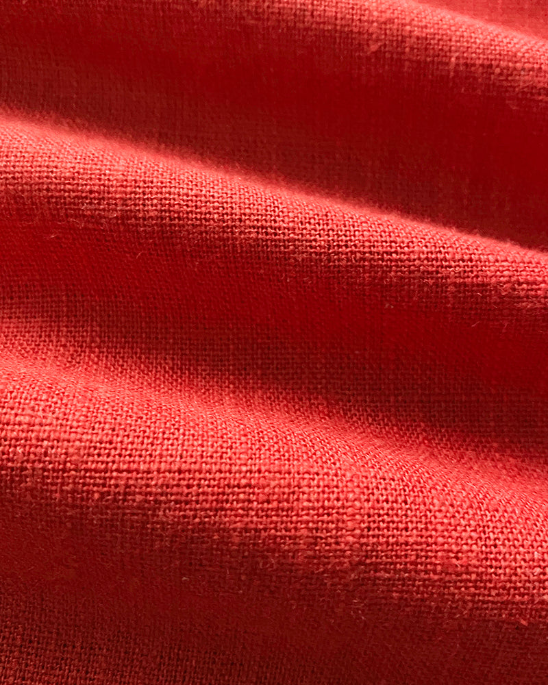 Textured red linen wrap top with visible weave and soft shadows accentuating fabric folds.