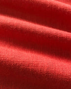 Textured red linen wrap top with visible weave and soft shadows accentuating fabric folds.