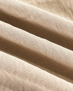 Close-up of beige woven blouse and wide leg pants with subtle sheen and soft texture.