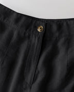 Black V-neck vest crop top and wide-leg pants with lion’s head gold button waistband.