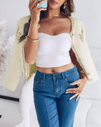 LA FINE FLEUR Pearl Button Fluffy Cardigan with Contrast Trim Coat, white strapless top, blue high-waisted jeans.