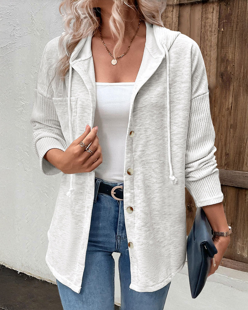 A long sleeve ribbed button-front hoodie with asymmetrical hem coat over white tank top and blue jeans.