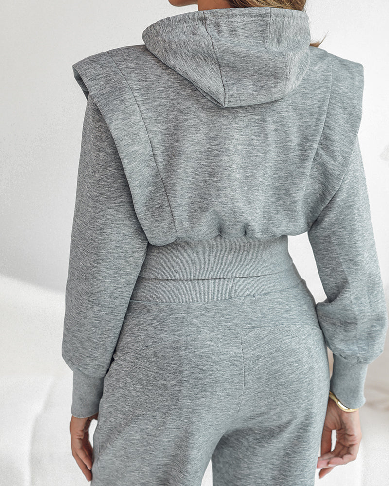 A light gray long sleeve hoodie with thumbholes and high-waisted wide-leg sweatpants.
