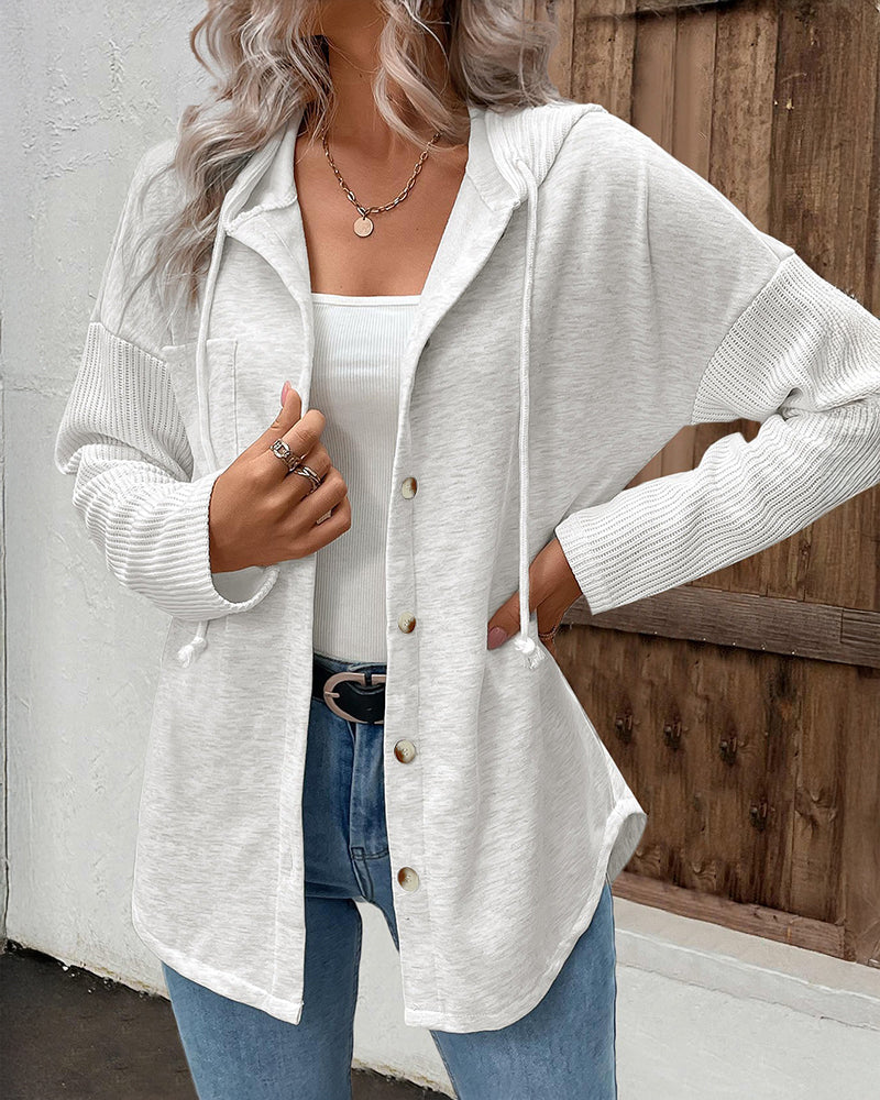 Long sleeve ribbed button-front hoodie coat with asymmetrical hem over a white top and blue jeans.