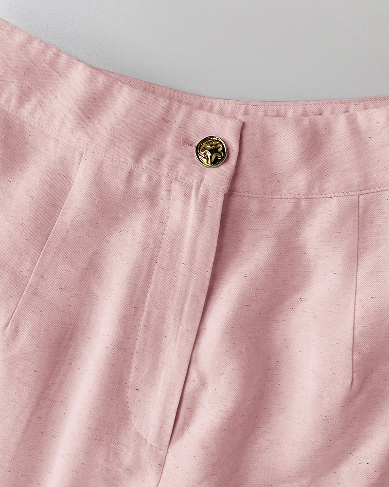 Light pink V-neck vest crop top and wide-leg pants with gold lion’s head button.