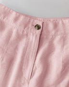 Light pink V-neck vest crop top and wide-leg pants with gold lion’s head button.
