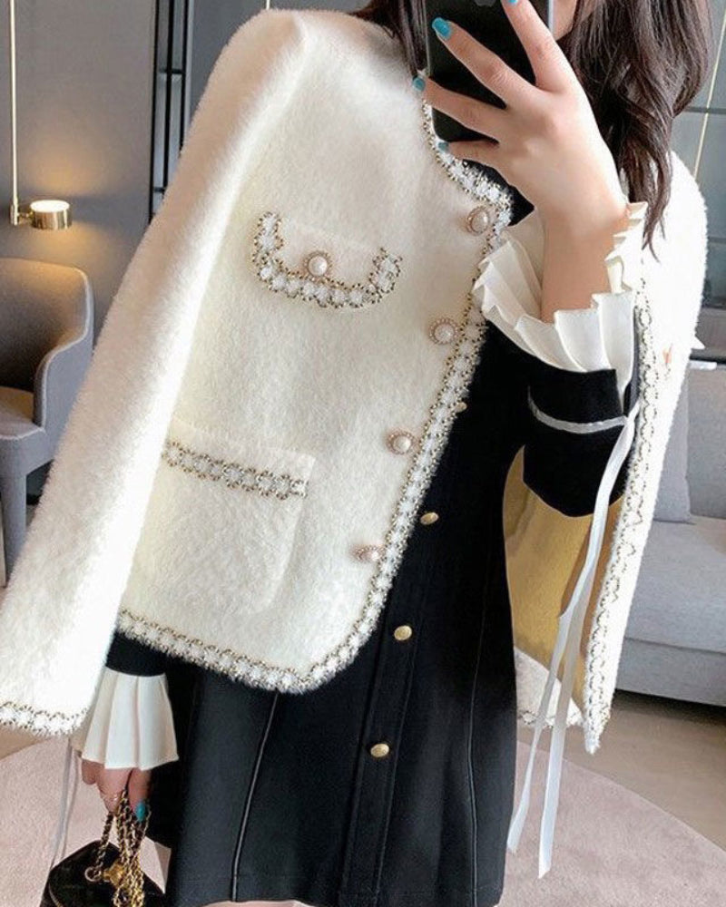 LA FINE FLEUR Pearl Button Fluffy Cardigan layered over a black dress with ruffled cuffs.