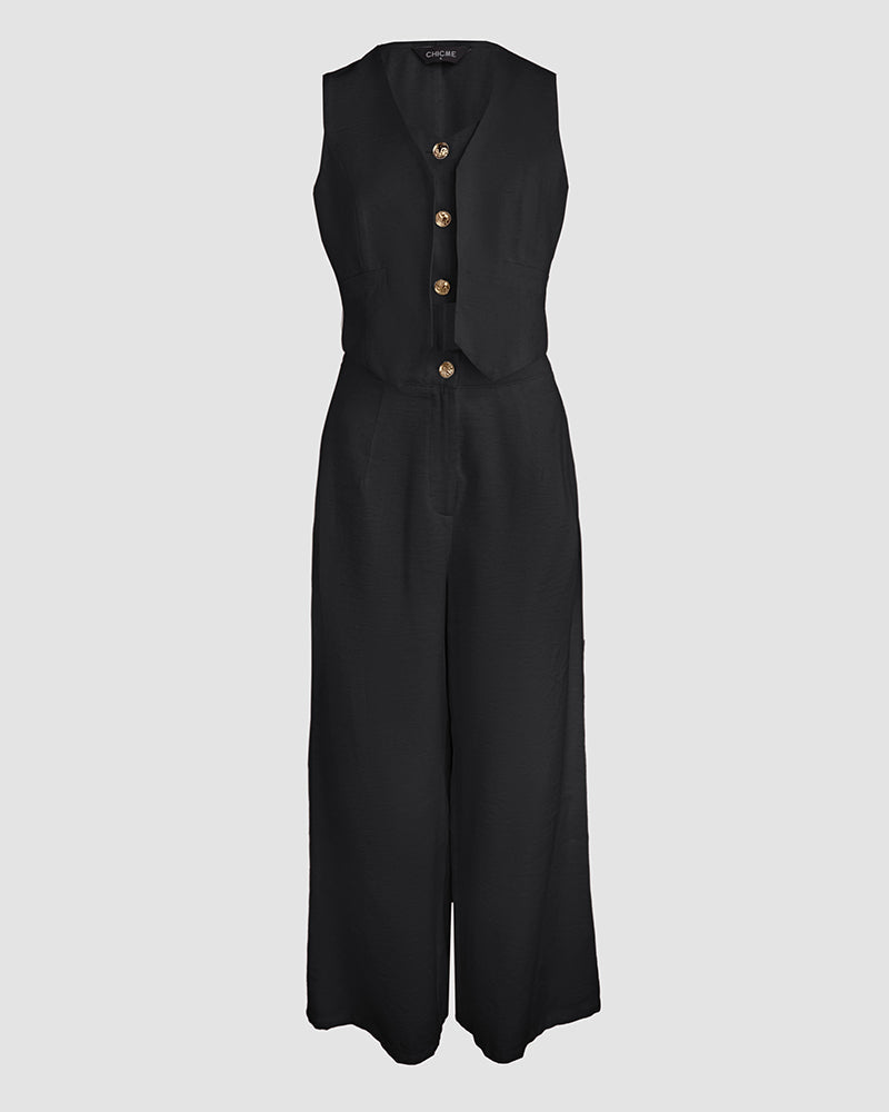 A black sleeveless V-neck vest crop top with wide-leg pants and three brown buttons.