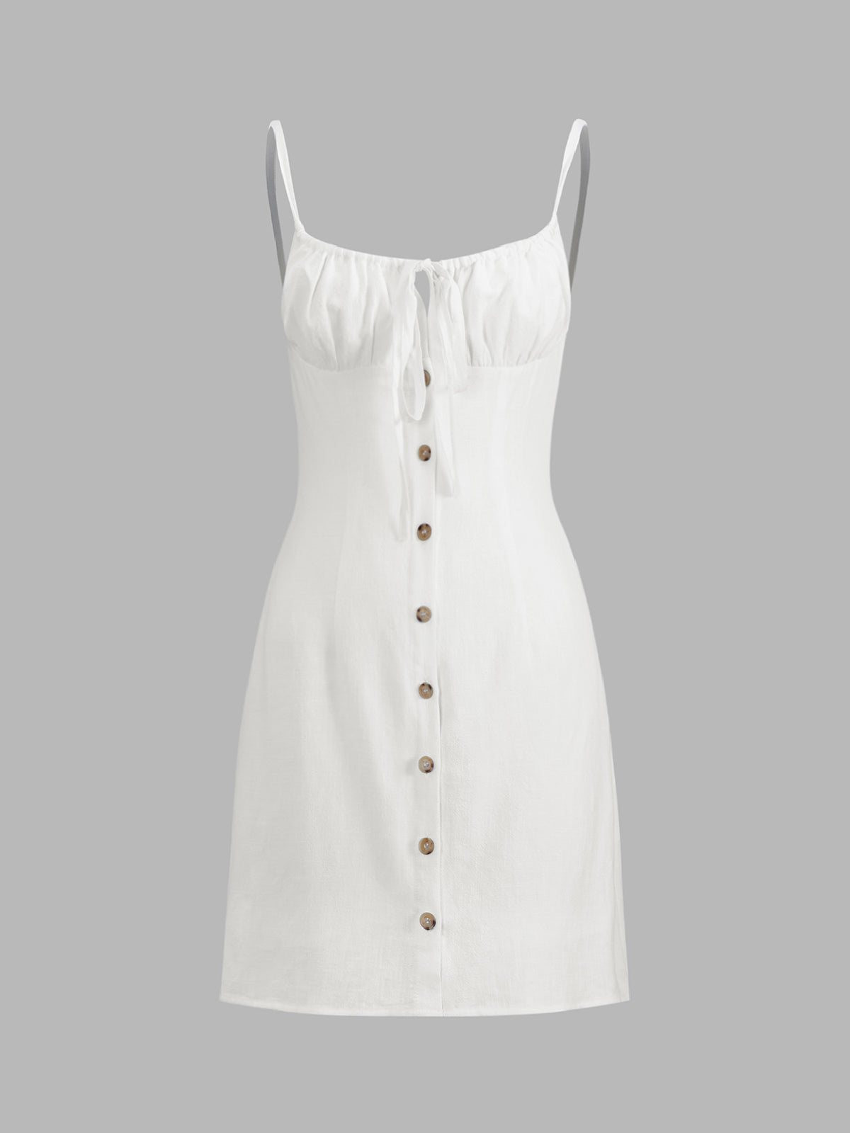 White sleeveless linen mini dress with thin straps, gathered bust tie, and brown buttons.