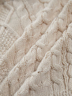 Cream-colored, sleeveless cable knit halter crop with drawstring and textured interwoven details.
