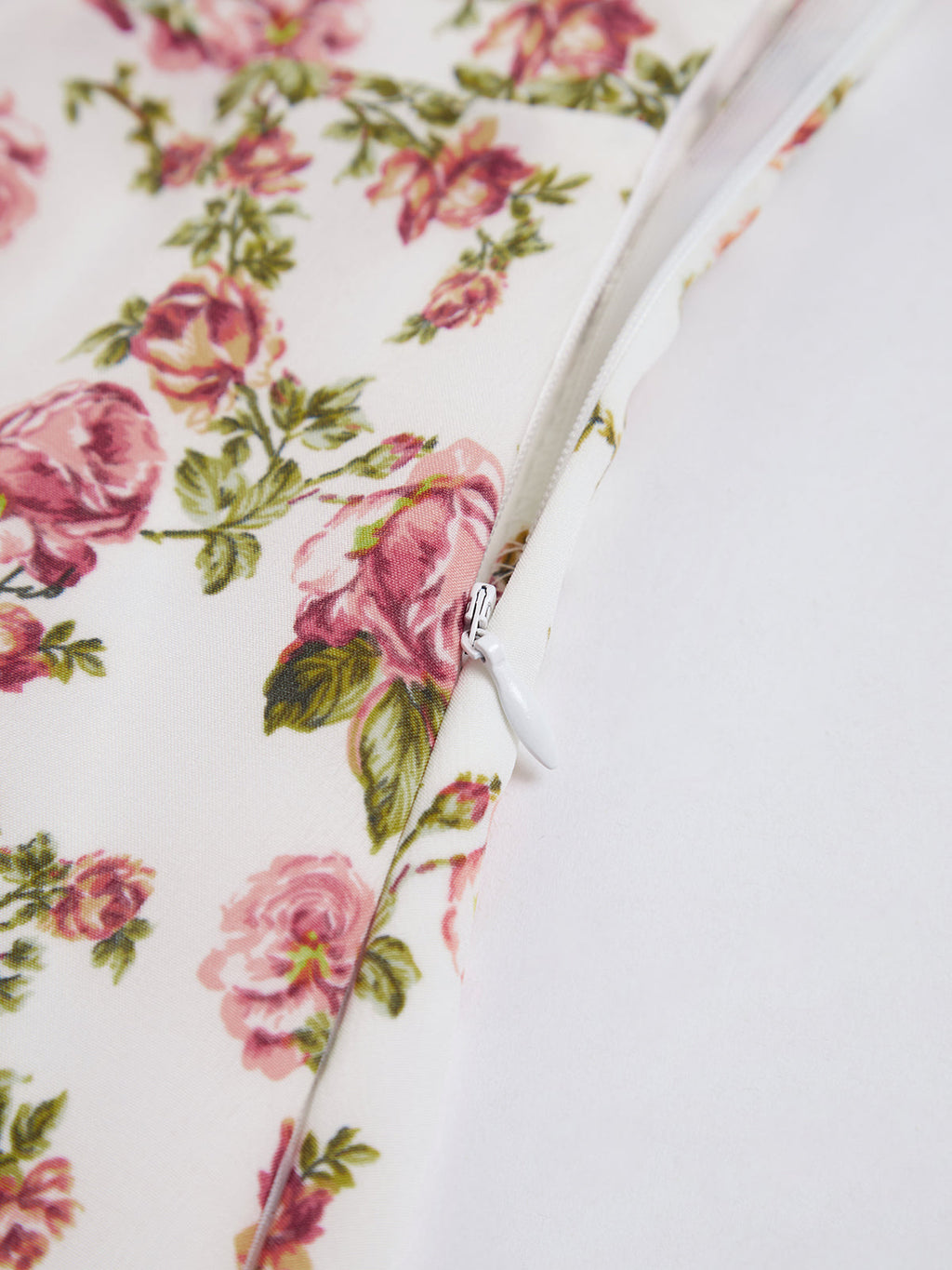White midi dress with pink floral print, featuring a partially unzipped white zipper and visible seams.