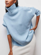 A Clear Sky Turtleneck Oversized Sweater with ribbed cuffs and hem, paired with a white skirt.