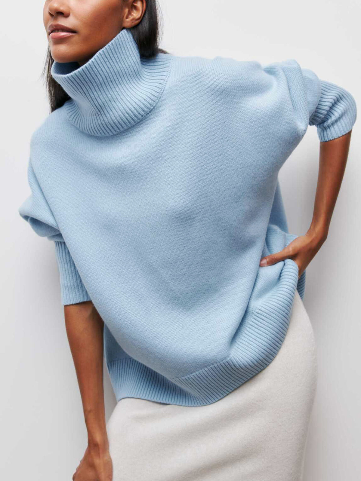 A Clear Sky Turtleneck Oversized Sweater with ribbed cuffs and hem, paired with a white skirt.