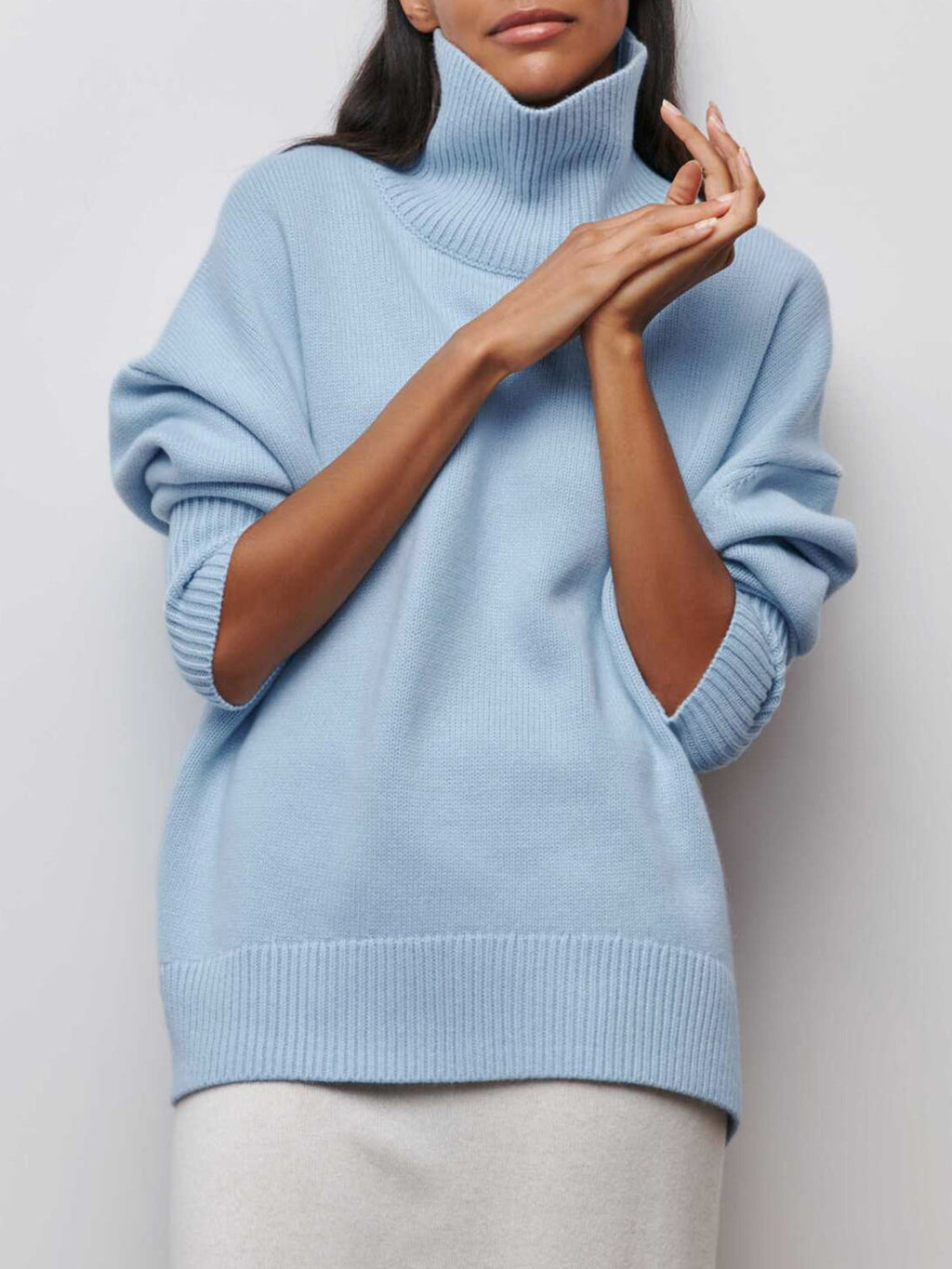 BYPINKYPARIS Clear Sky Turtleneck Oversized Sweater with pushed-up sleeves, paired with a white skirt.