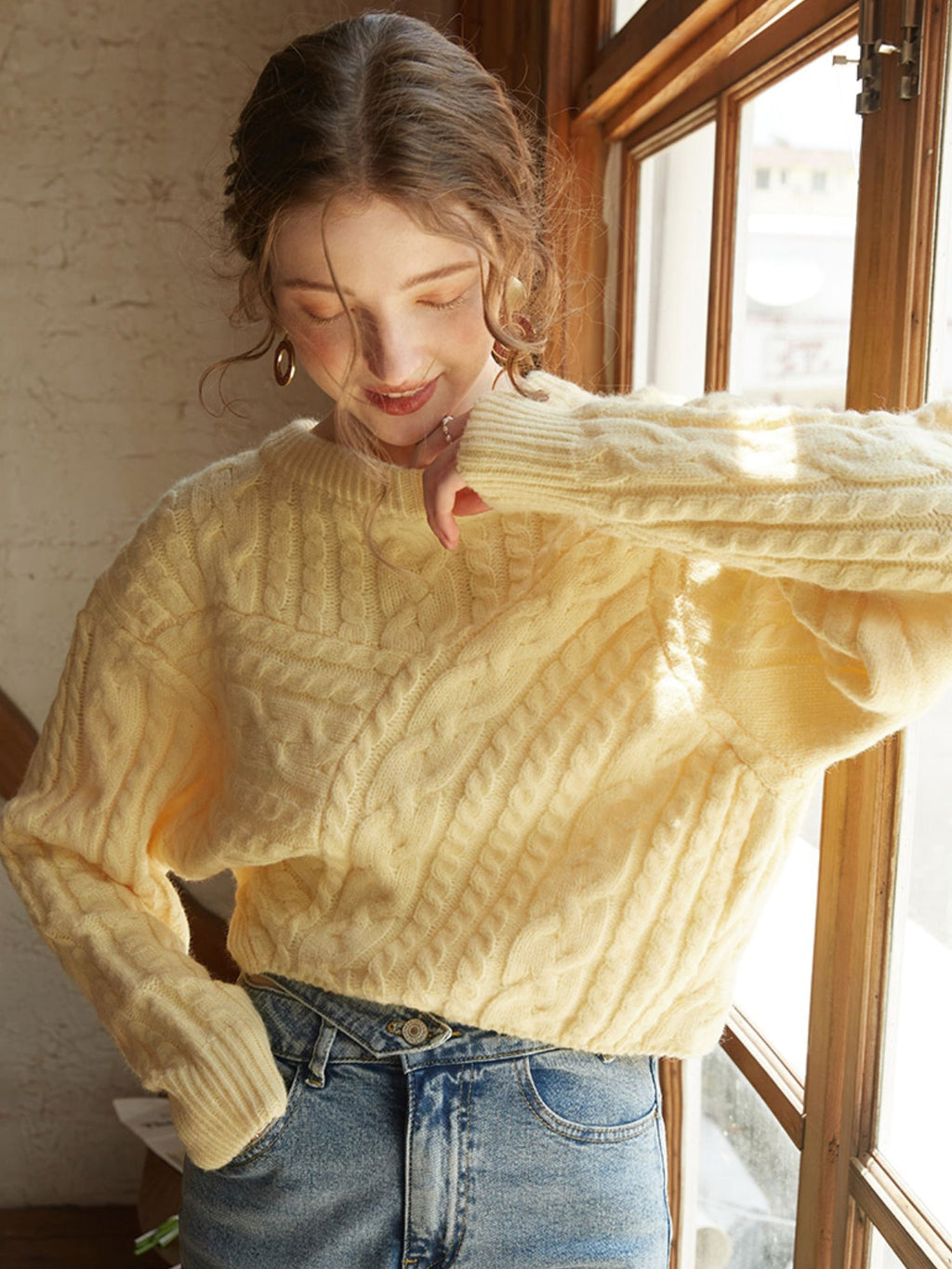 Oversized knit sweater in a vibrant limoncello hue paired with classic blue jeans.