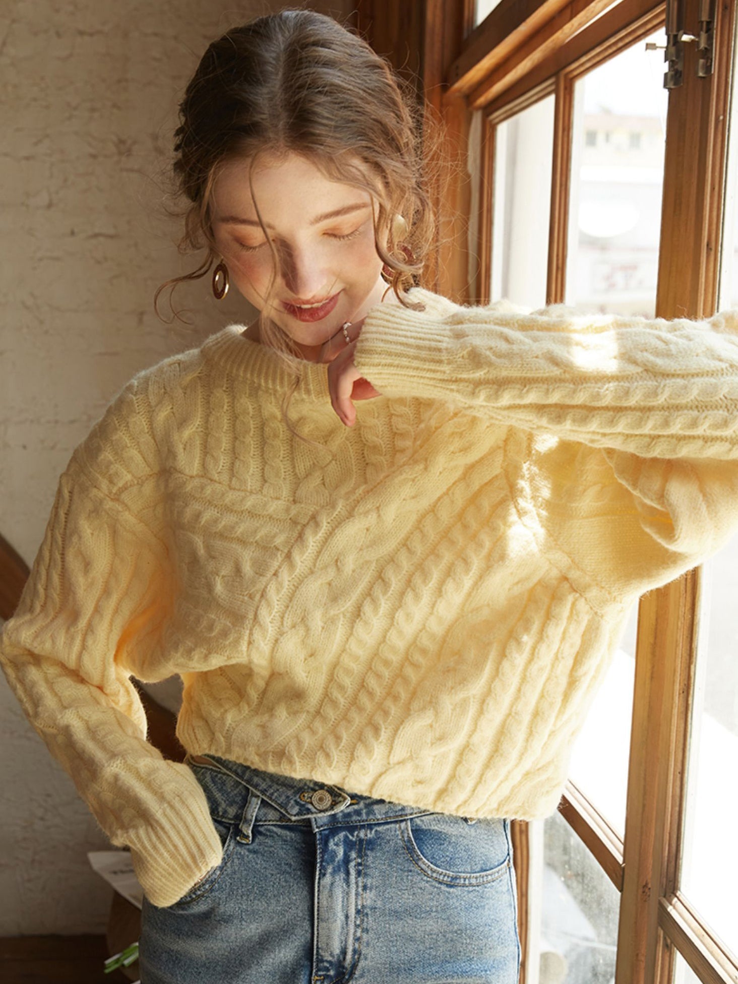 Oversized knit sweater in a vibrant limoncello hue paired with classic blue jeans.
