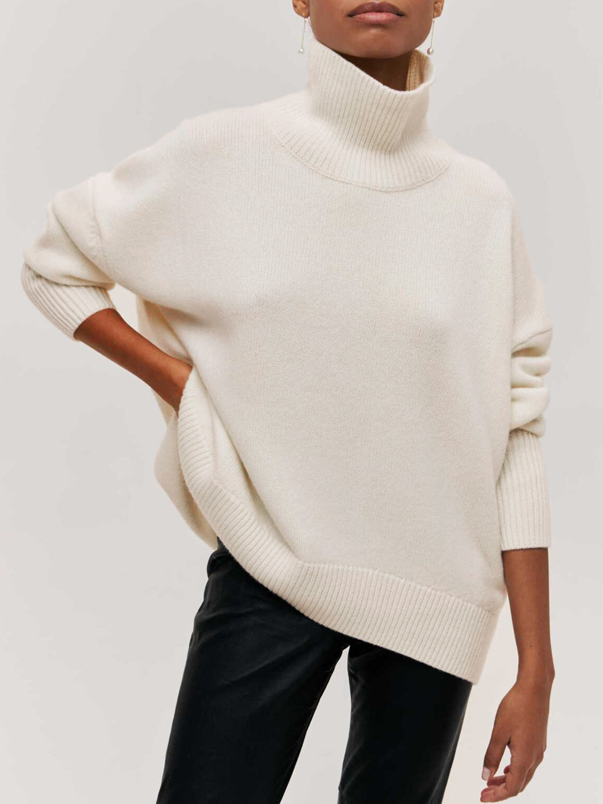 Cream BYPINKYPARIS Clear Sky oversized turtleneck sweater with ribbed cuffs, paired with black pants.