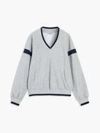 Light gray V-neck sweatshirt with navy striped sleeves, contrast trim, pockets, and relaxed fit.