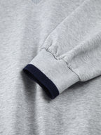 Light gray oversized sweatshirt with long jersey sleeves, navy trim, and elastic cuffs.