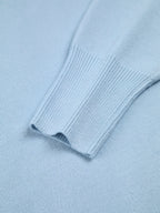Close-up of blue turtleneck sweater sleeve, showing ribbed cuff and smooth knit fabric.