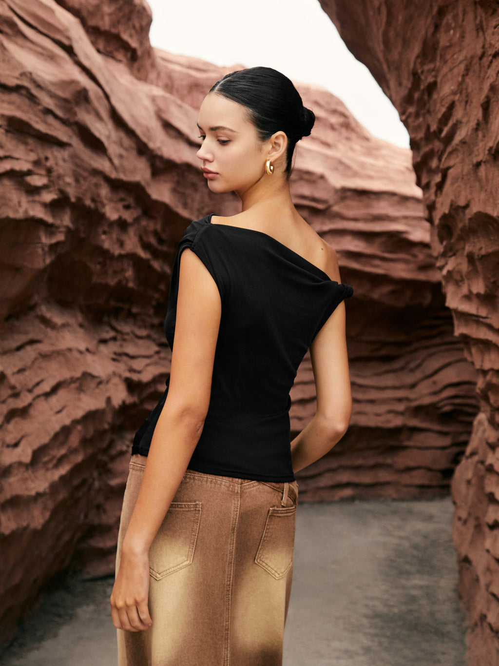 LA FINE FLEUR Unique One-Shoulder Top with Elegant Side Knot paired with tan pants.