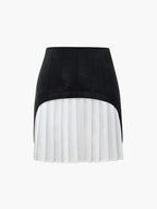A black faux leather patchwork mini skirt with a high-low hem and white pleated insert.