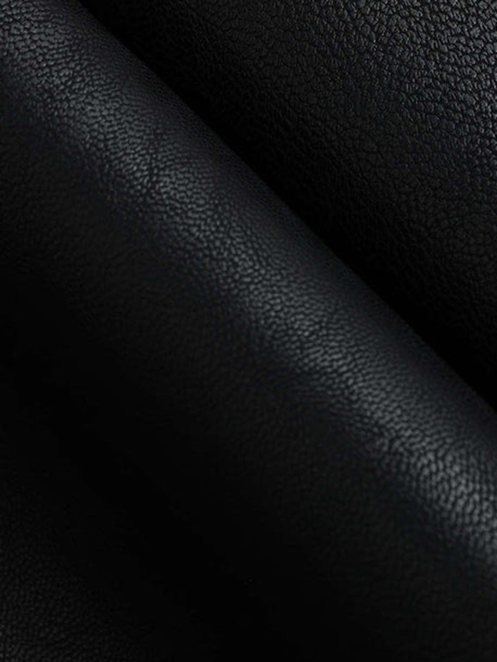 Black faux leather mini skirt with pebbled texture and soft pleats creating gentle shadows.