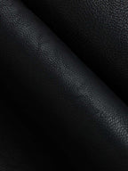 Black faux leather mini skirt with pebbled texture and soft pleats creating gentle shadows.