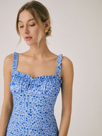 A blue, sleeveless floral midi dress with ruffled straps and a ruffled neckline.