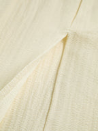 Cream-colored textured dress fabric with crinkled pattern and visible seam stitching details.