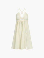 Cream midi dress with a halter neckline, crisscross back straps, and split flowy hem.