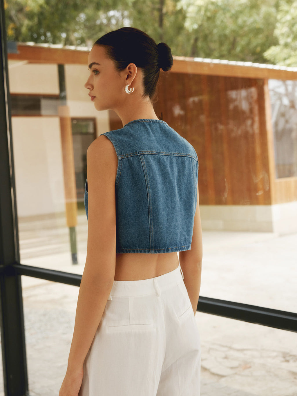 Sleeveless crop top denim shirt with double pockets, paired with white pants.
