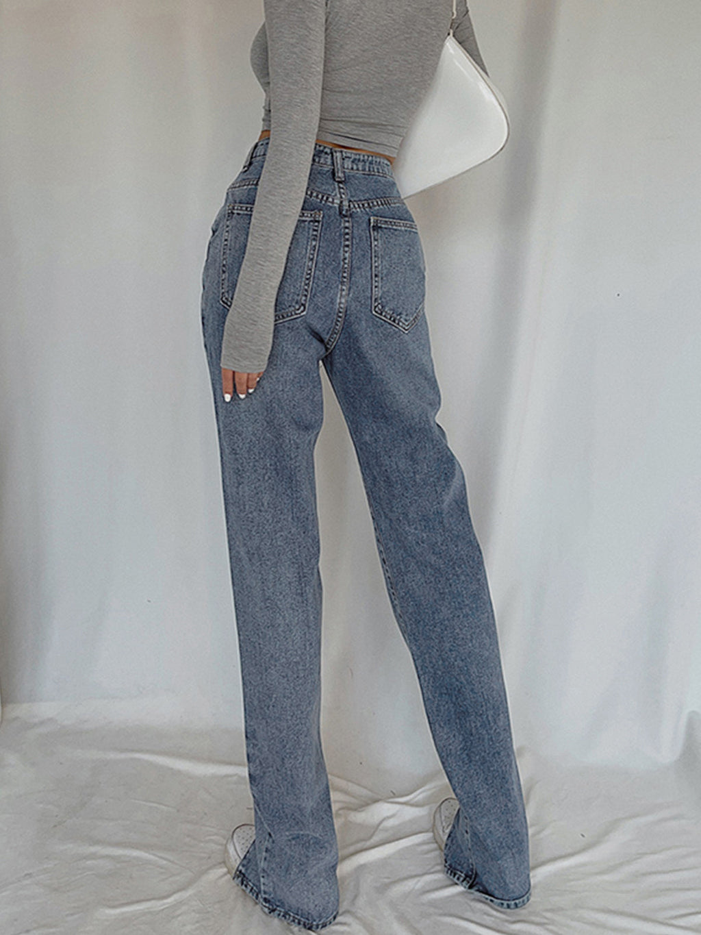 Classic straight leg denim jeans with a long-sleeve gray crop top and white shoes.