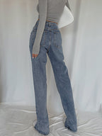Classic straight leg denim jeans with a long-sleeve gray crop top and white shoes.