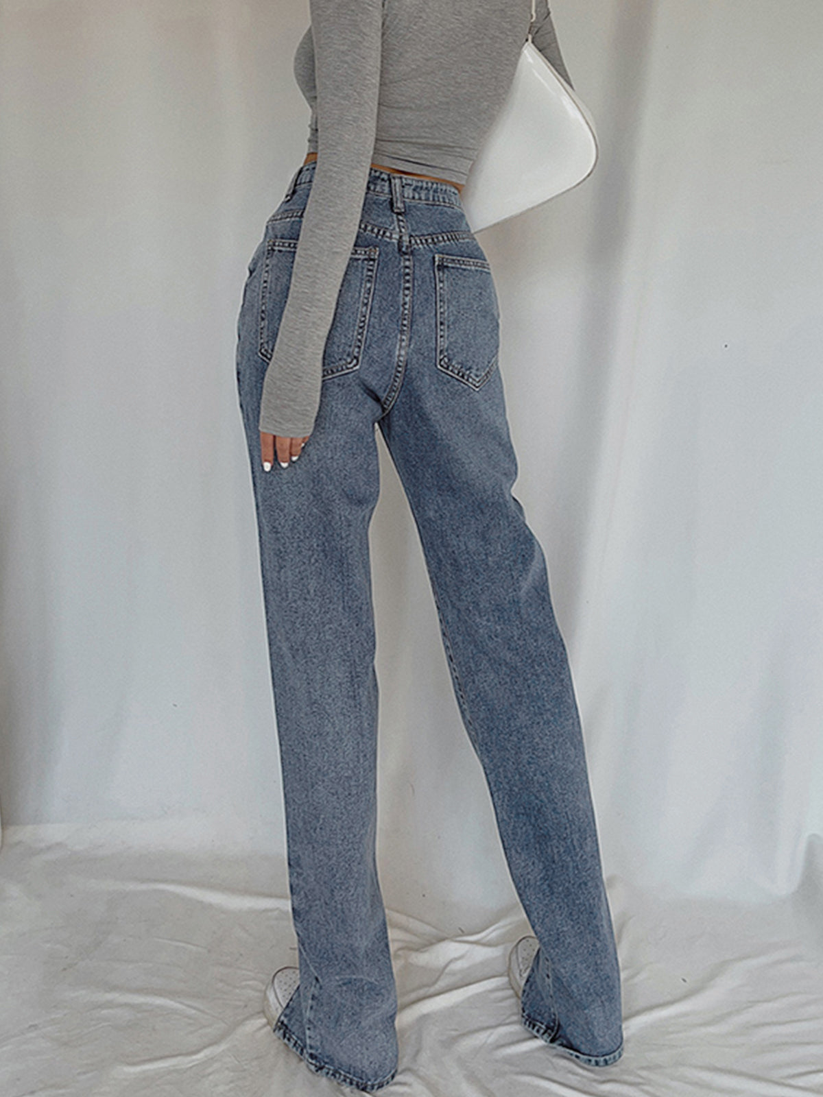Classic straight leg denim jeans with a long-sleeve gray crop top and white shoes.