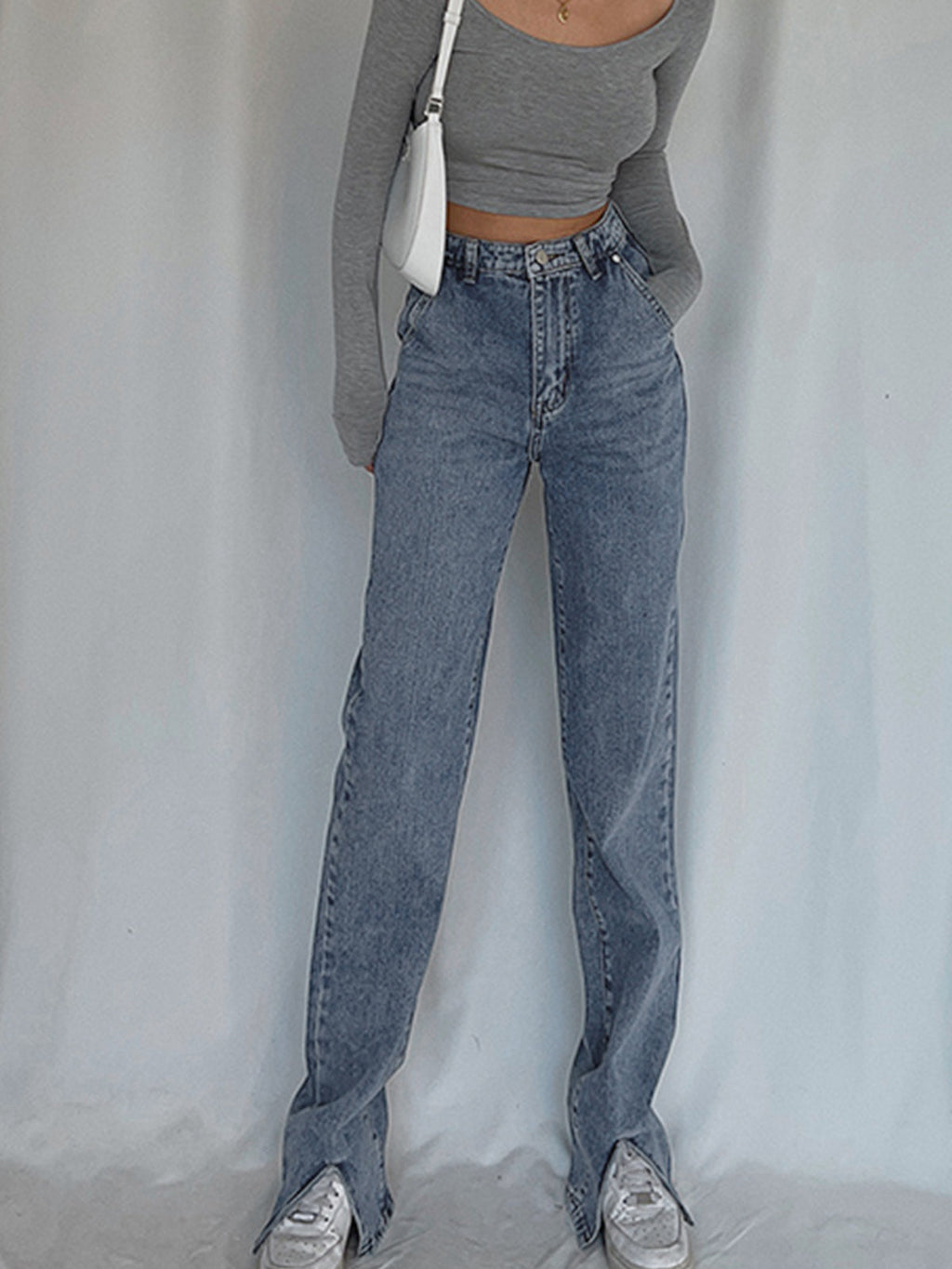 Classic straight leg denim jeans and a fitted gray long-sleeve crop top are worn.