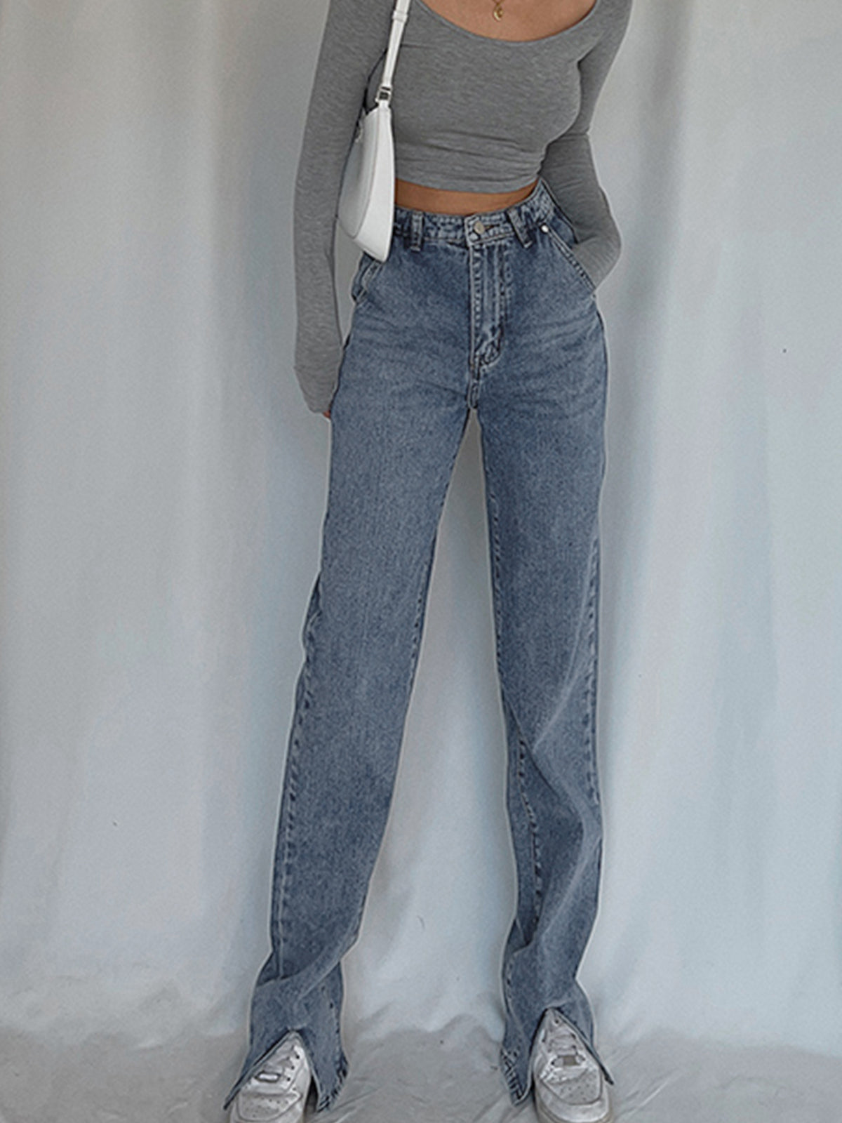 Classic straight leg denim jeans and a fitted gray long-sleeve crop top are worn.