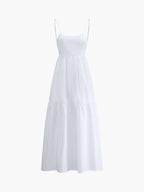 A white maxi dress with thin spaghetti straps, open back, and tiered flowing skirt.