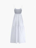 White maxi dress with thin spaghetti straps, gathered waist, open back, and tiered skirt.