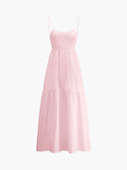 Light pink sleeveless maxi dress with thin straps, open back, fitted bodice, tiered skirt.