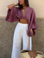 LA FINE FLEUR mauve long sleeve cropped tie-front blouse and high-waisted white wide-leg pants.