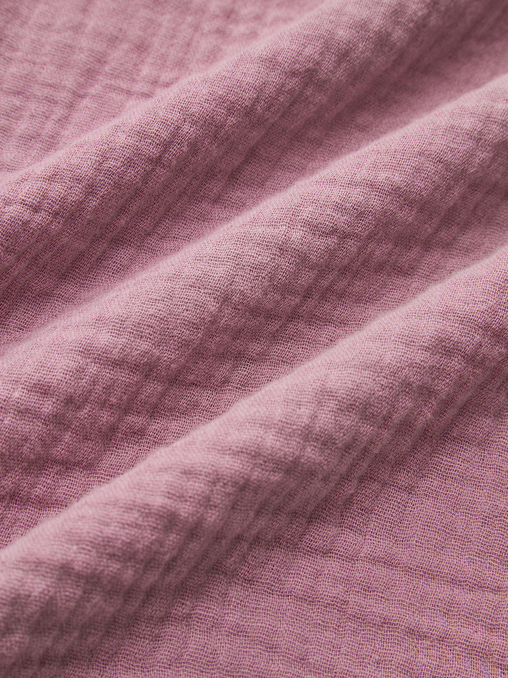 Close-up of mauve long sleeve cropped blouse fabric, highlighting woven texture and diagonal folds.