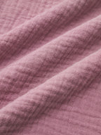 Close-up of mauve long sleeve cropped blouse fabric, highlighting woven texture and diagonal folds.