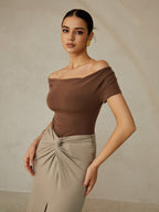 A brown off-shoulder pleated tee paired with a beige gathered-knot skirt.