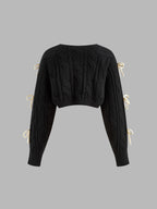 Black cropped cable knit cardigan with elegant bow-knots along the long sleeves.