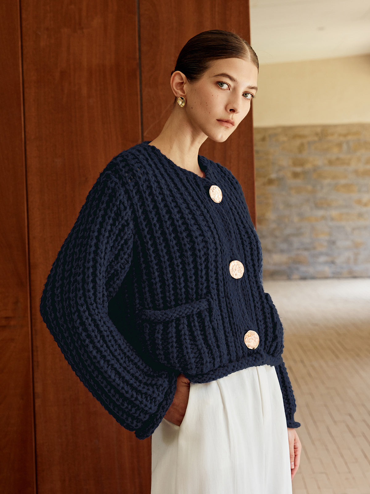 Chunky navy soft knit cardigan with large gold buttons, styled with a white skirt.