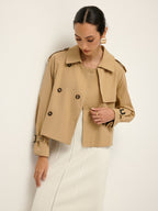 LA FINE FLEUR double-breasted lapel trench coat with tailored fit over long textured white skirt.