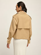 Double-breasted lapel trench coat with tailored fit, layered over a white ribbed skirt.