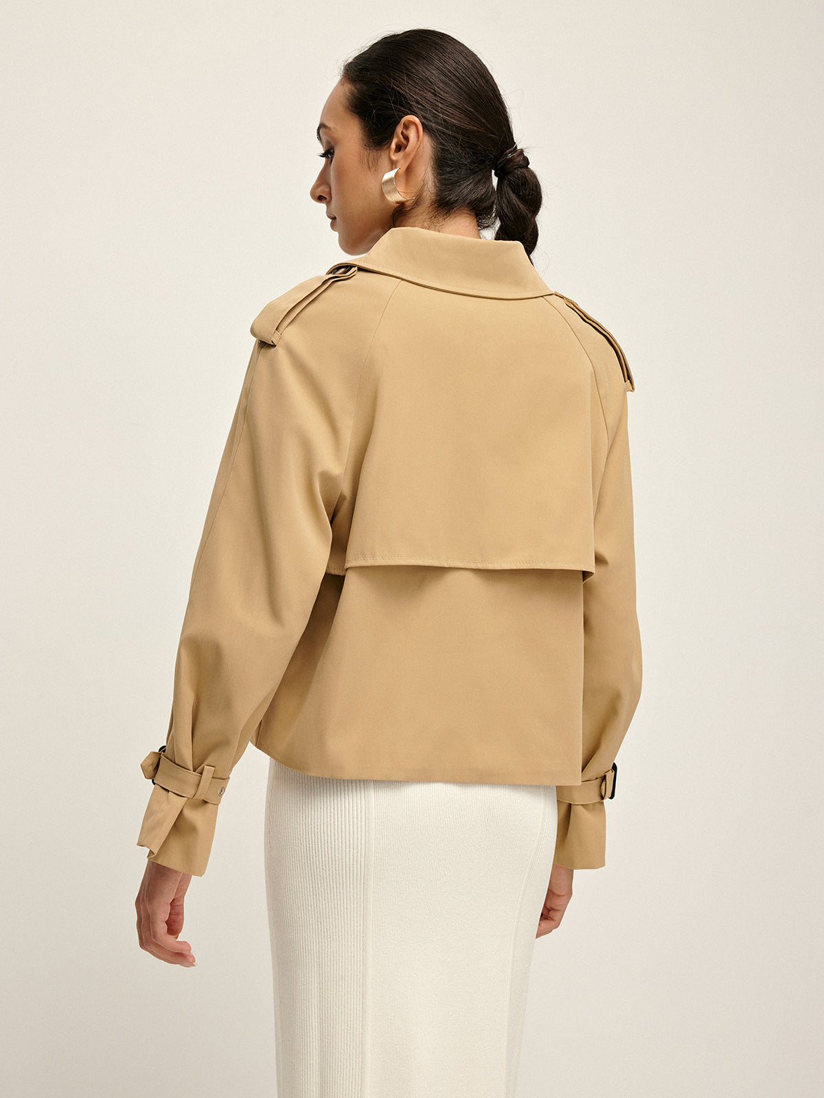 Double-breasted lapel trench coat with tailored fit, layered over a white ribbed skirt.